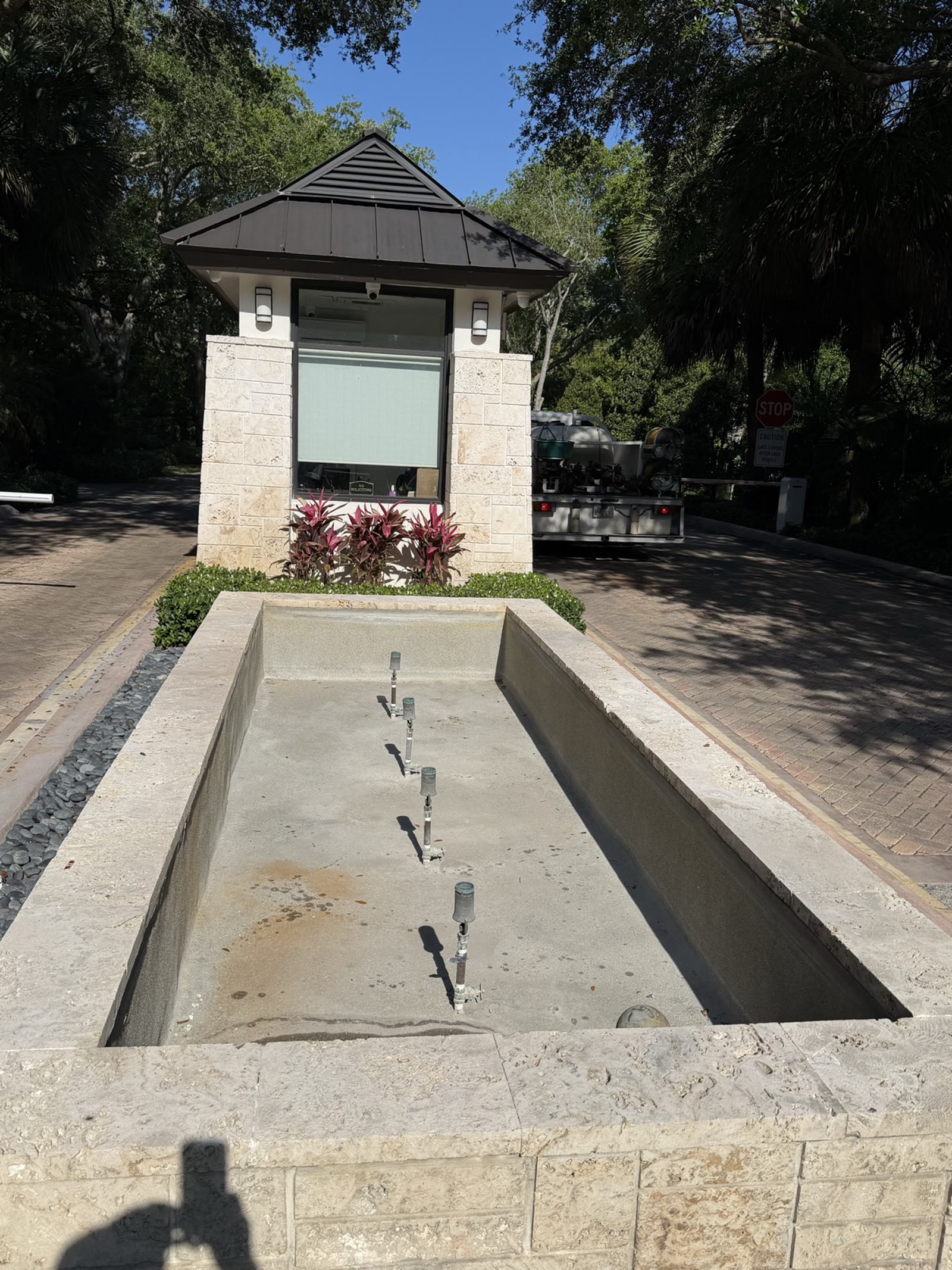 Empty stone water trough at a property entry, dry and stained