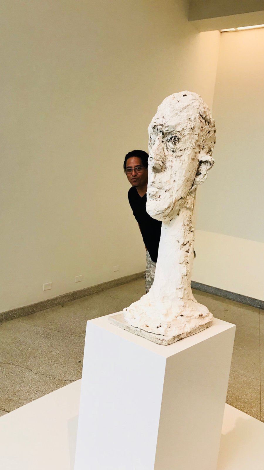 Lee at the Guggenheim behind a Giacometti sculpture